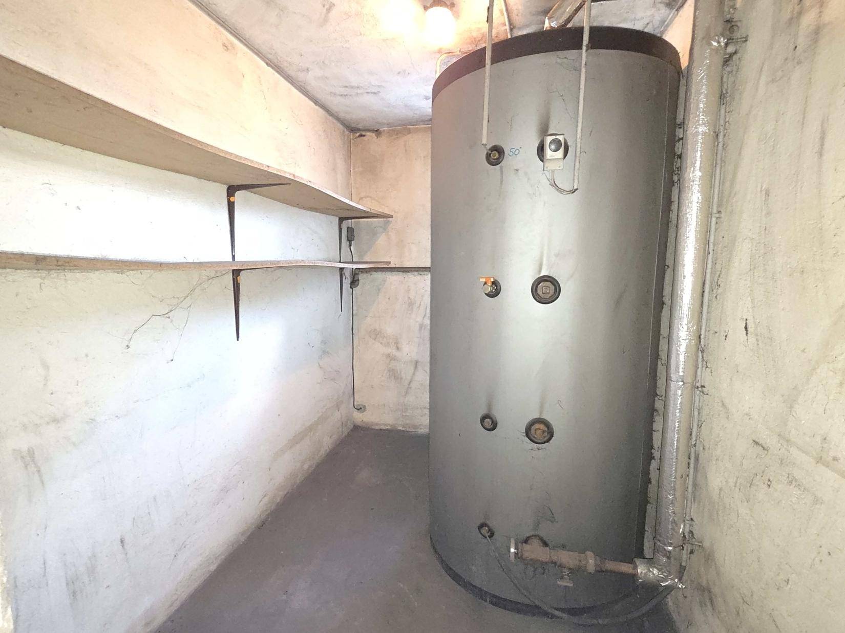 Kellerraum mit großem Warmwasserspeicher und Regalen für zusätzlichen Stauraum.