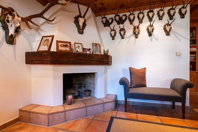 Gemütlicher Kaminbereich mit rustikalem Holzbalken und traditionellen Fliesen im Wohnzimmer.