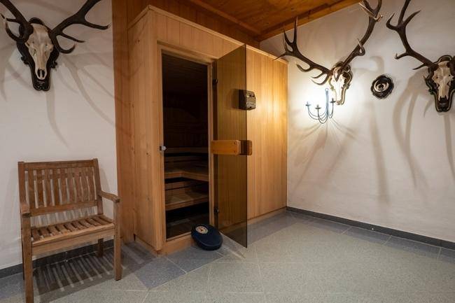 Wellnessbereich mit einer Holzsauna und Hirschgeweihen an den Wänden, die eine rustikale Atmosphäre schaffen.