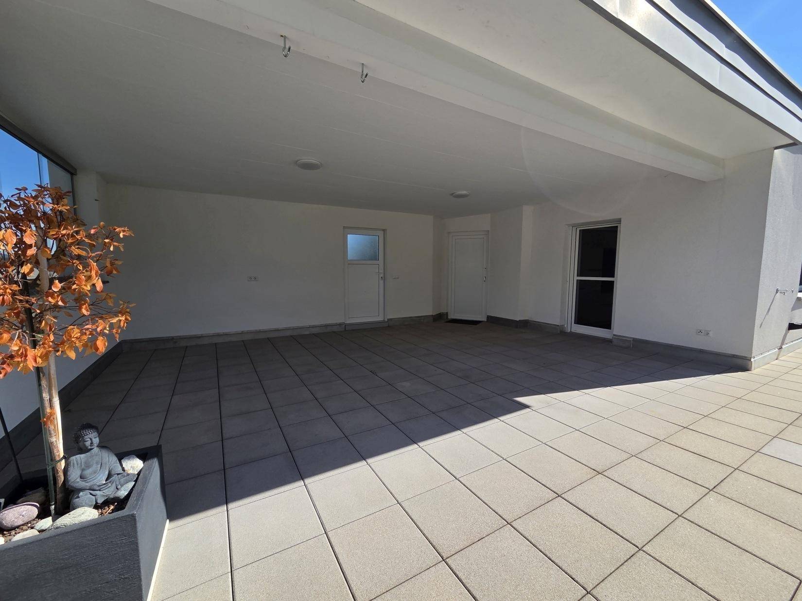 Weitläufige, überdachte Terrasse mit Fliesenboden und mehreren Zugängen zum Innenbereich.