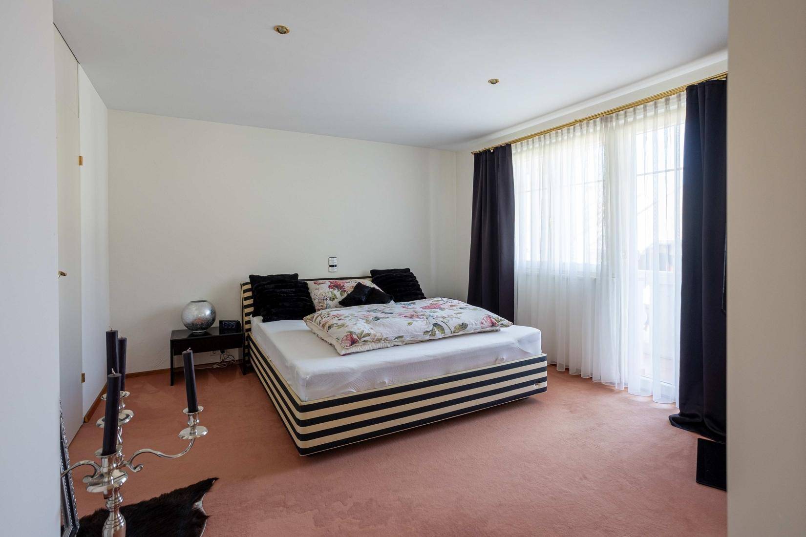 Geräumiges Schlafzimmer mit Teppichboden, großem Bett und viel Tageslicht.