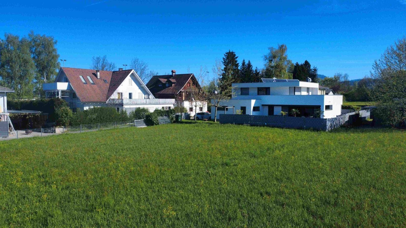 Panoramablick auf eine moderne Villa mit großem Rasen und umliegender grüner Landschaft.