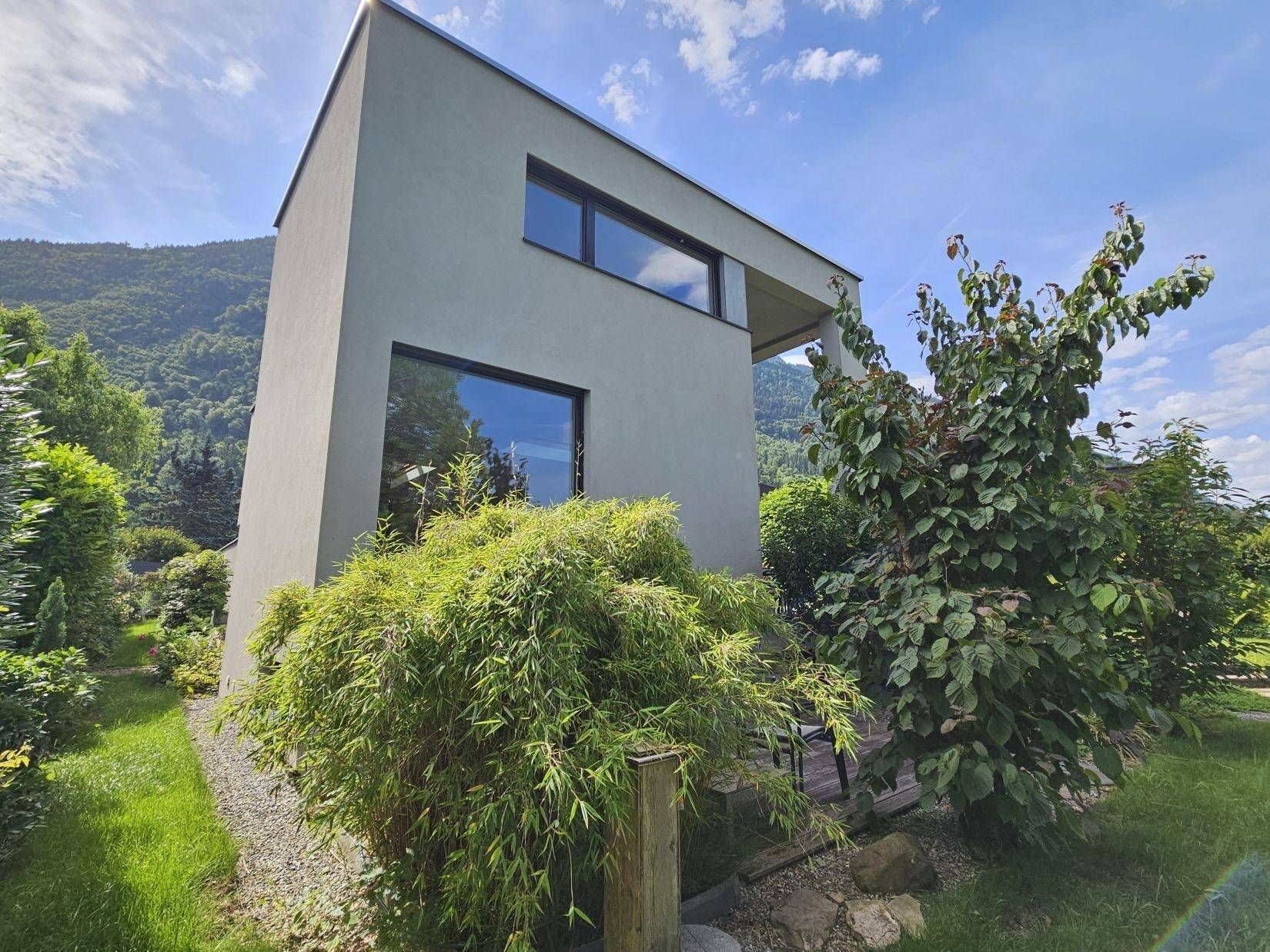 Seitenansicht des modernen Hauses, harmonisch eingebettet in die grüne Umgebung.