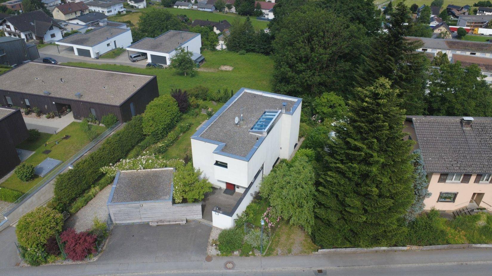 Luftaufnahme des Hauses mit Garage, Garten und der angrenzenden Straße.