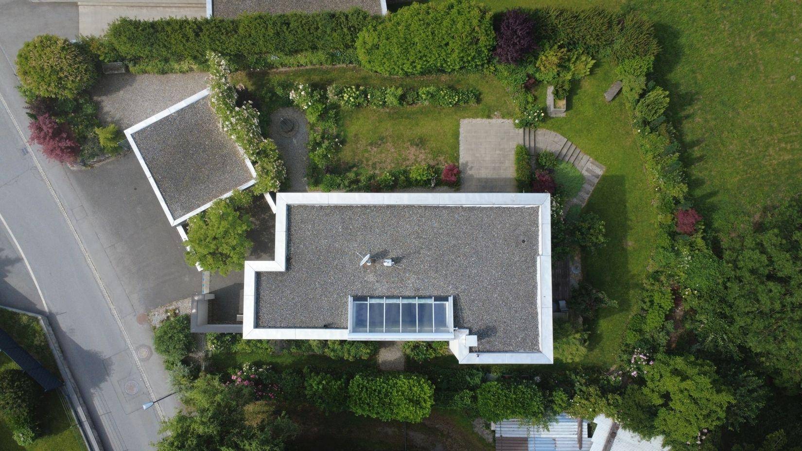 Draufsicht des Hauses mit Flachdach, Oberlicht und dem umliegenden Gartenbereich.