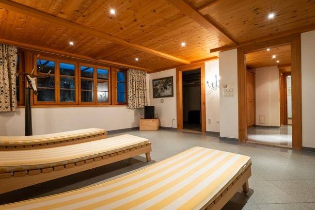 Entspannungsbereich mit Liegestühlen, Holzwänden und einem Fenster, das den Raum mit natürlichem Licht füllt.