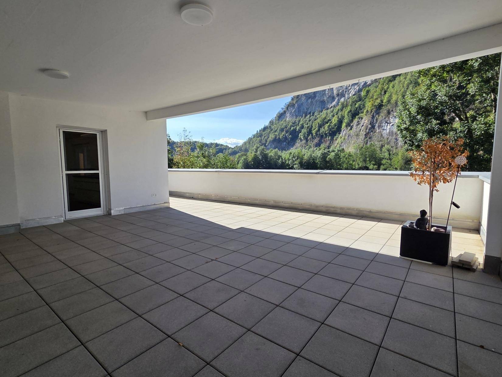 Geräumige, überdachte Terrasse mit Fliesenboden und Panoramablick auf die umliegende Natur.