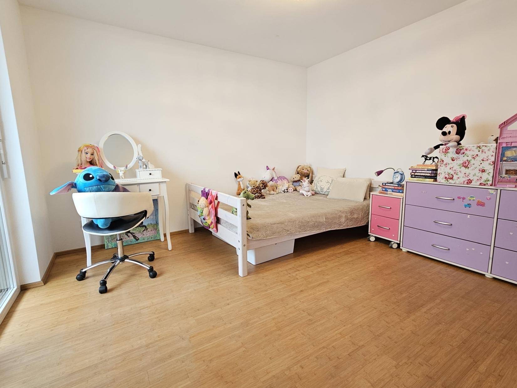 Kinderzimmer mit Holzboden, Bett und Spielzeug, hell und freundlich eingerichtet.