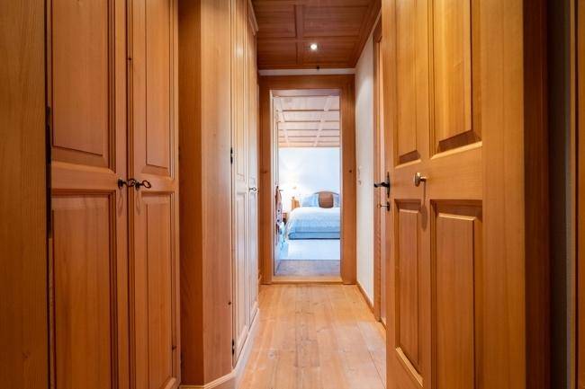 Langer Flur mit Holzvertäfelung und Einbauschränken, der zu einem weiteren Schlafzimmer führt.