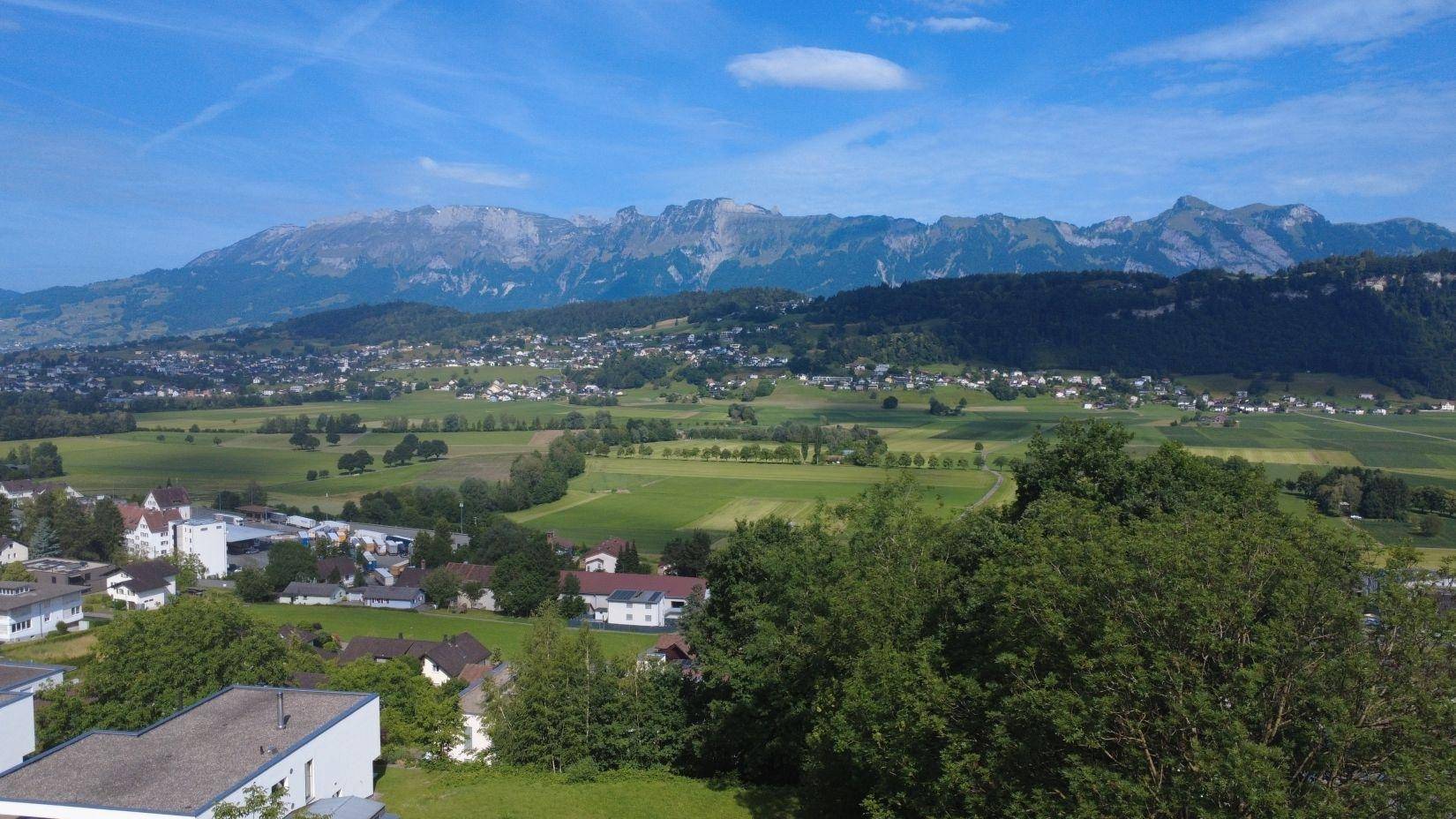 Panoramablick über das Tal mit Bergen, Feldern und der umliegenden Wohnbebauung.