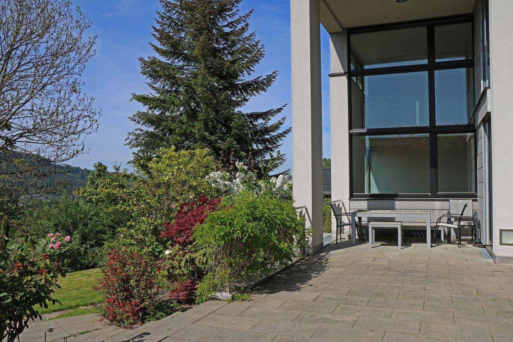 Geräumige Terrasse mit Sitzgelegenheiten, umgeben von Grün und mit weitem Ausblick.