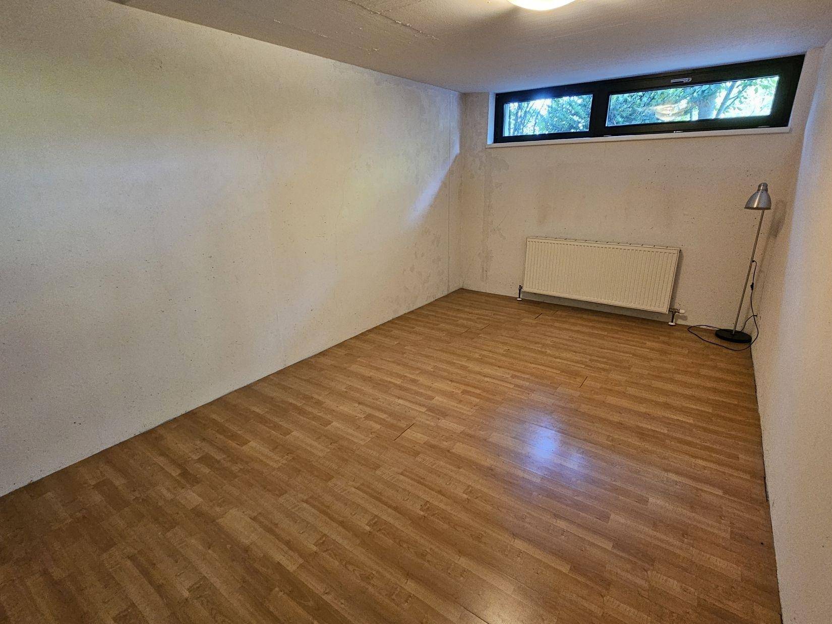 Kellerraum mit Laminatboden und Heizkörper, nutzbar als Hobbyraum oder zusätzliches Zimmer.