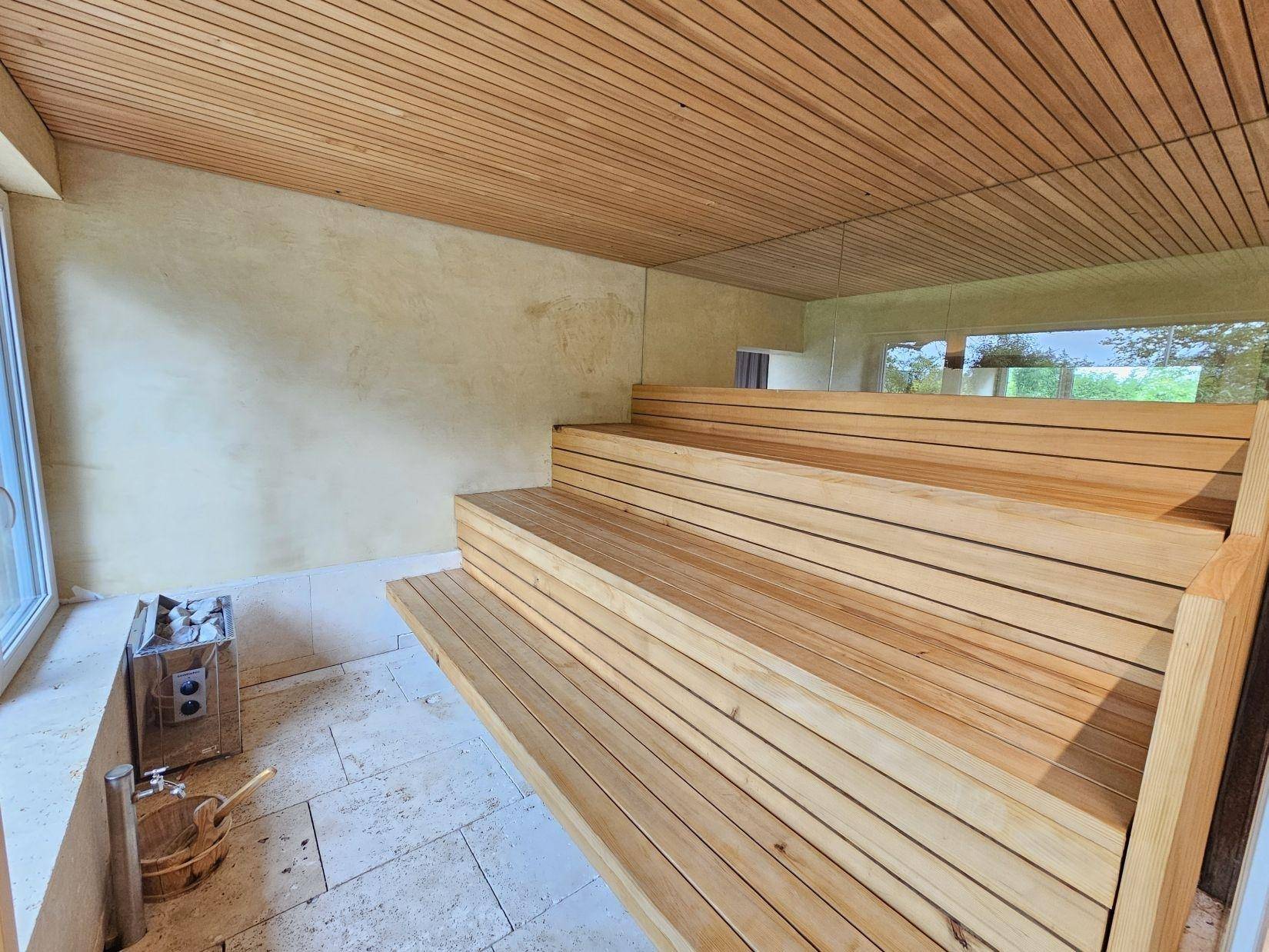 Geräumige Holzsauna mit mehreren Stufenbänken und einer Decke aus Holzpaneelen für Entspannung.