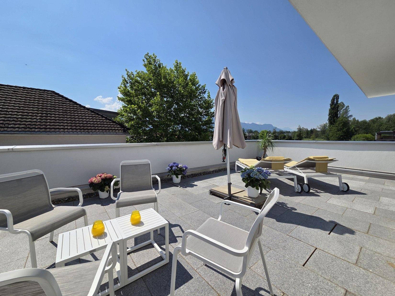 Geräumige Dachterrasse mit Essbereich und Sonnenliegen, perfekt für gesellige Stunden im Freien.