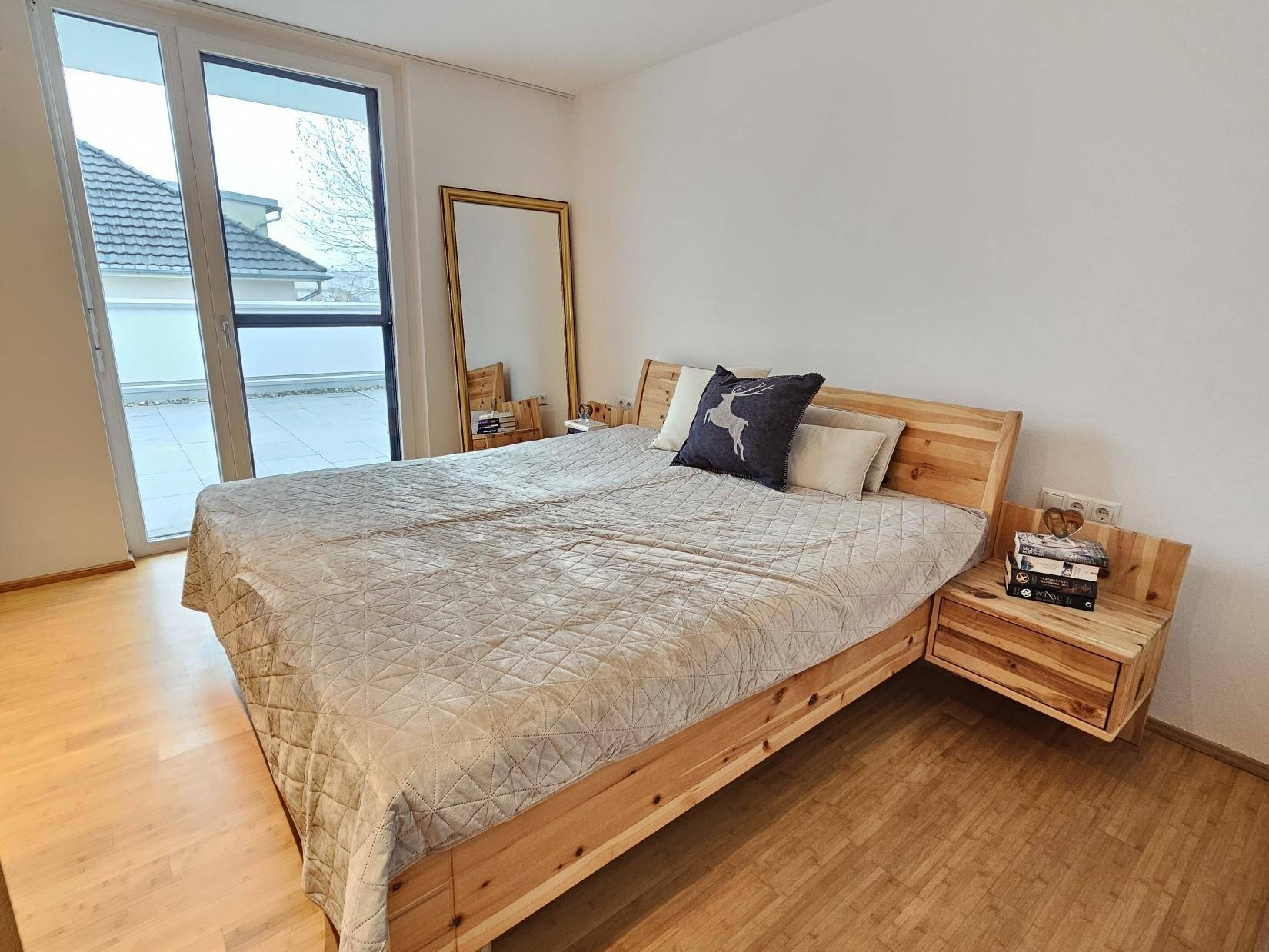 Gemütliches Schlafzimmer mit Holzbett, Nachttischen und Zugang zu einer großen Terrasse.