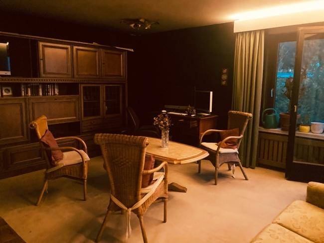 Gemütliches Wohnzimmer mit Korbmöbeln, Teppichboden und Zugang zum Außenbereich.
