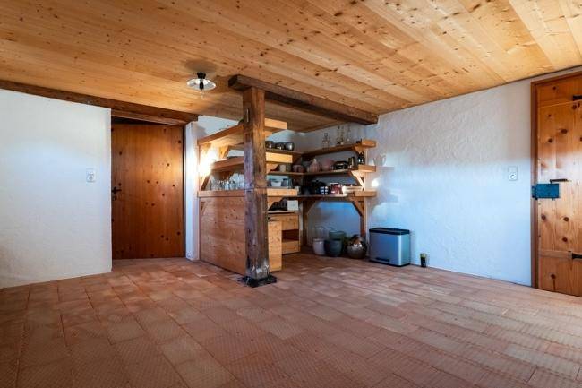 Rustikaler Abstellraum mit Holzregalen und Terrakotta-Bodenfliesen, der viel Stauraum bietet.