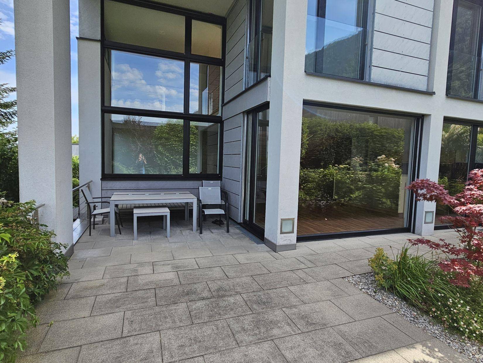 Sonniger Terrassenbereich mit modernen Gartenmöbeln und Zugang zum Garten.