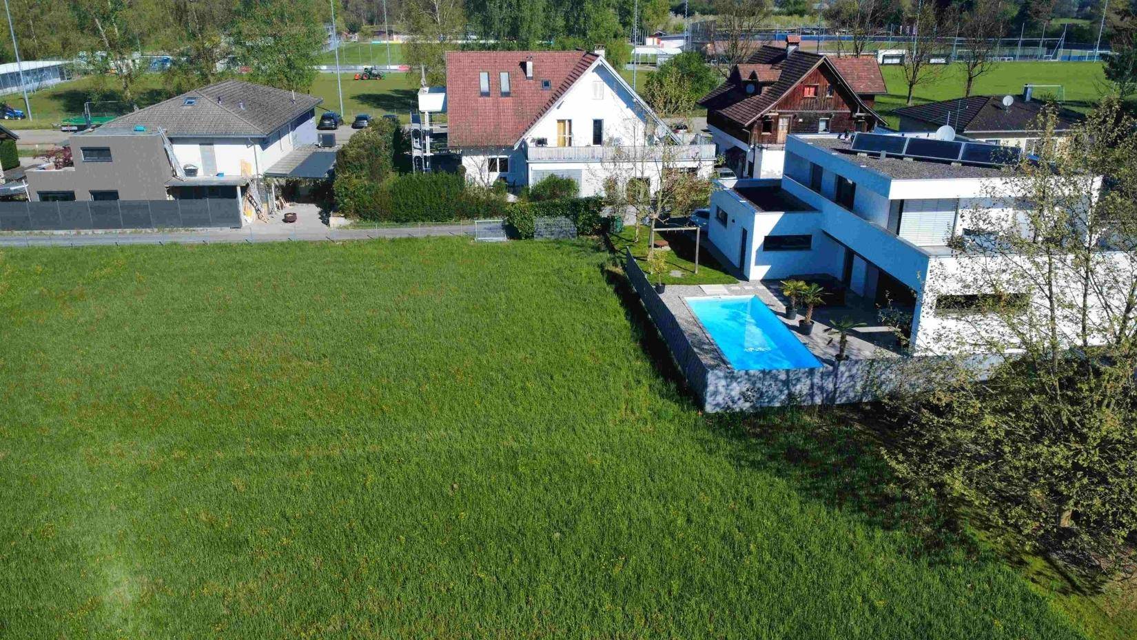 Luftaufnahme einer modernen Villa mit Pool und großem Garten, umgeben von Natur.