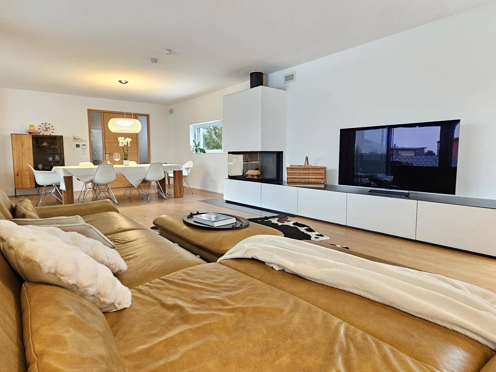 Geräumiger Wohn- und Essbereich mit Kamin, Holzboden und moderner Einrichtung.
