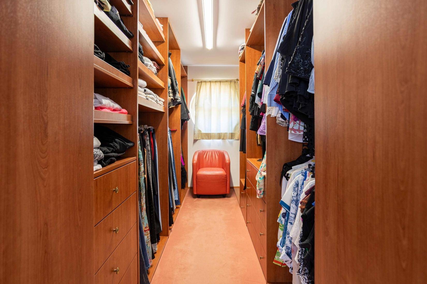 Begehbarer Kleiderschrank mit maßgefertigten Holzregalen und viel Stauraum.