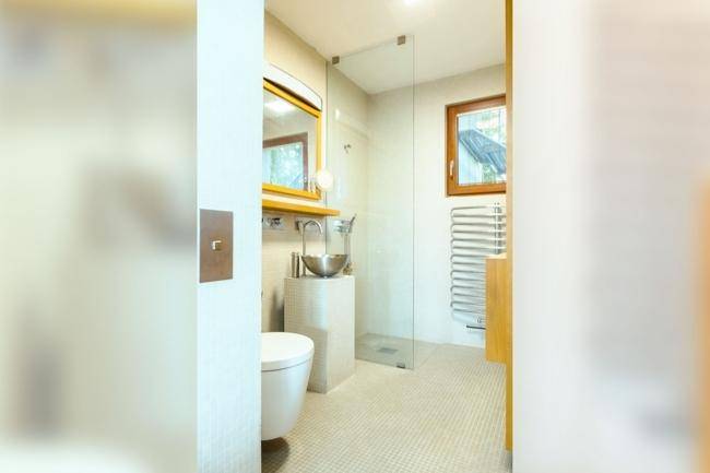 Modernes Badezimmer mit Duschkabine, kleinem Waschbecken und beheiztem Handtuchhalter.