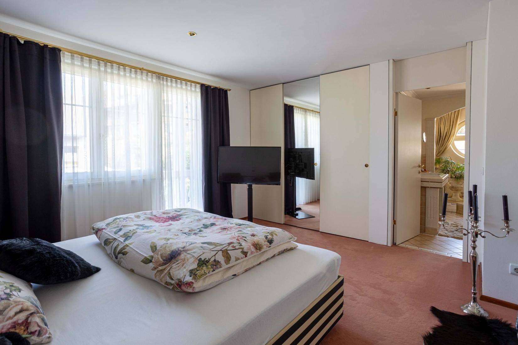 Schlafzimmer mit Teppichboden, Einbauschränken und direktem Zugang zum Badezimmer.