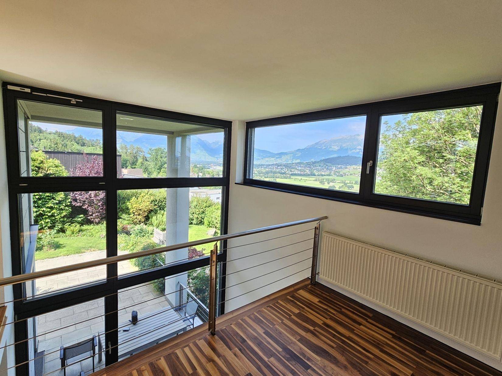 Offener Galeriebereich mit Holzparkett, Edelstahlgeländer und weitem Blick in die Landschaft.