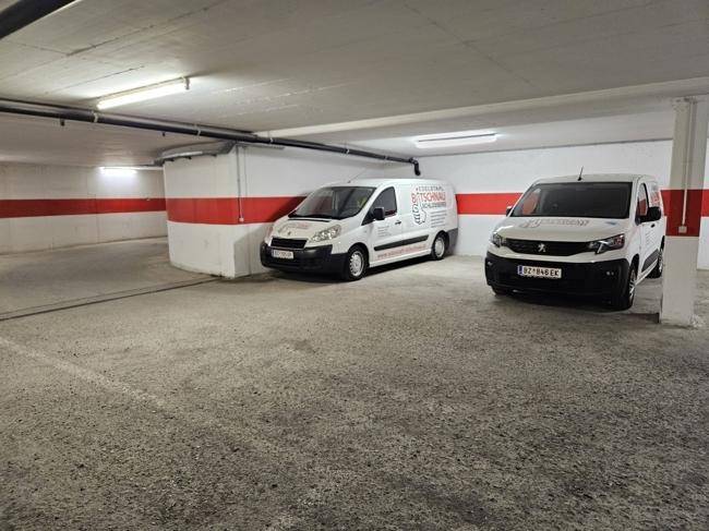 Weitläufige Tiefgarage mit geparkten Lieferwagen und klaren Markierungen an den Wänden.