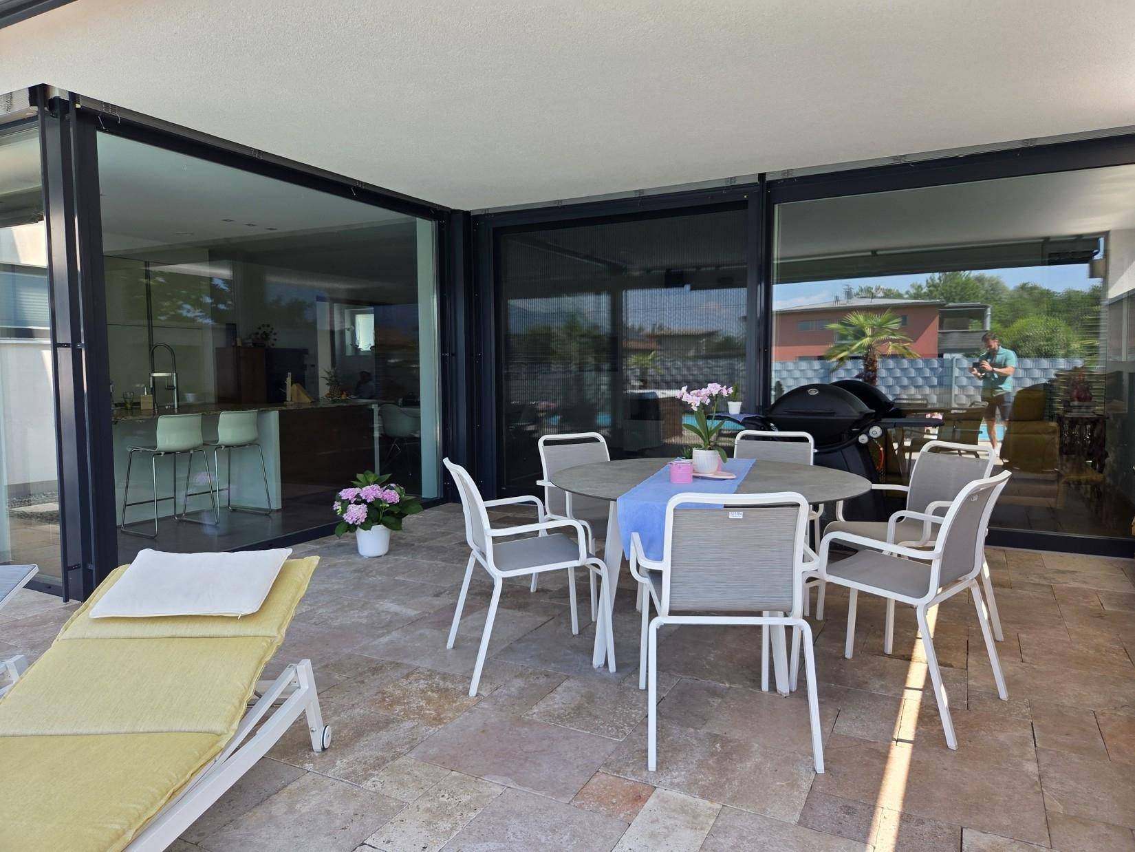 Gemütlicher Essbereich im Freien auf der Terrasse, direkt angrenzend an den Wohnbereich mit großen Glasfronten.