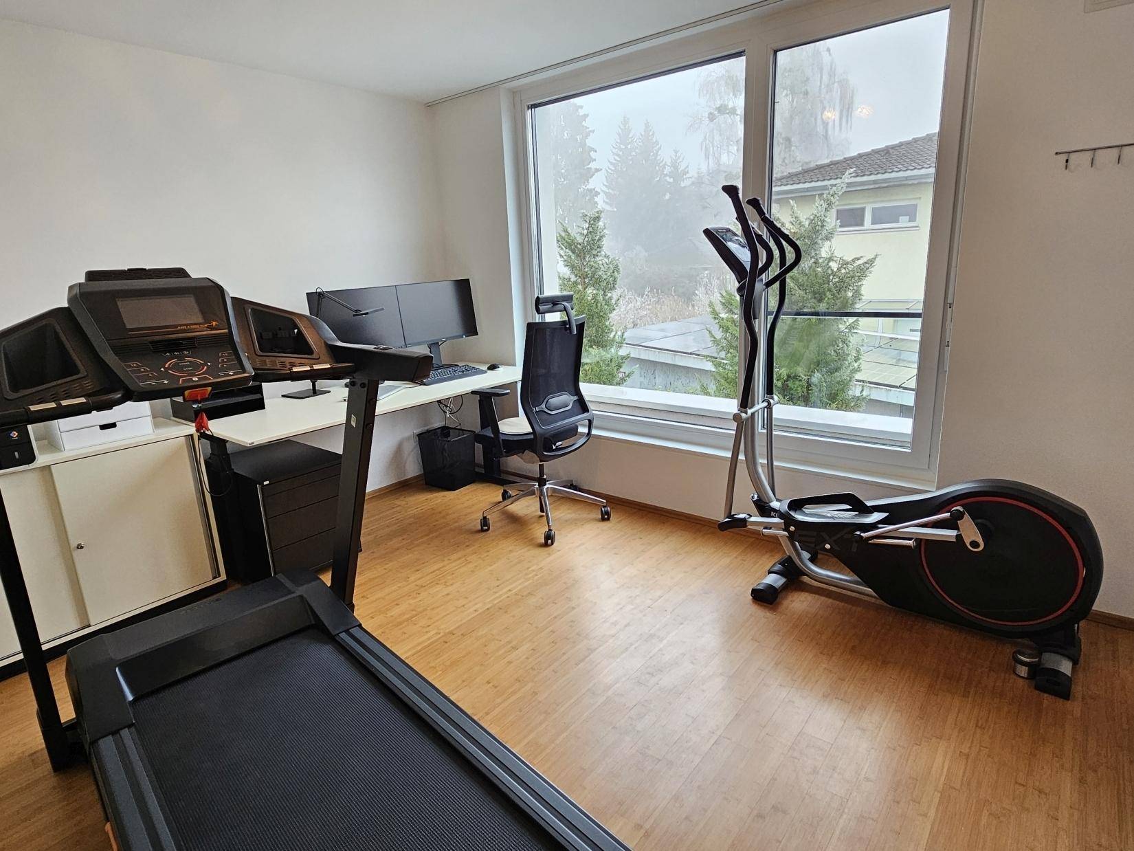 Helles Arbeitszimmer mit großen Fenstern, Laufband und Crosstrainer für Sport und Arbeit.