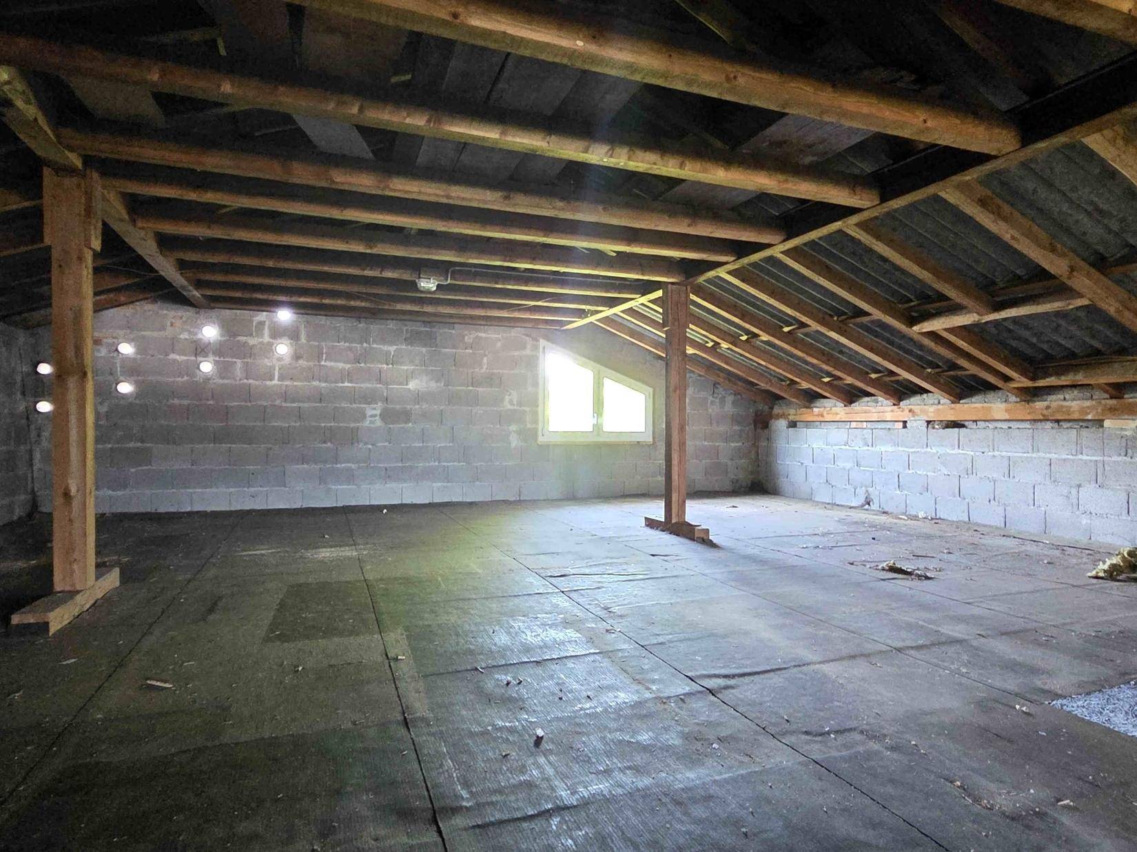 Geräumiger Dachboden mit sichtbaren Holzbalken und Fenster, bietet Ausbaupotenzial.