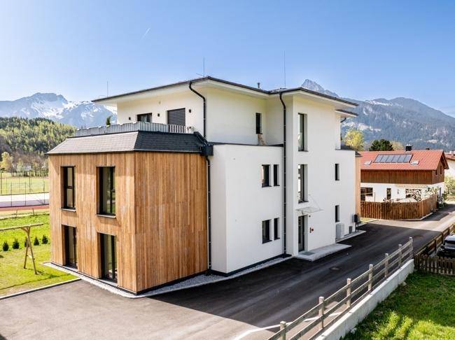 Rückansicht des modernen Gebäudes mit Holzfassade und Zufahrt zur Tiefgarage.