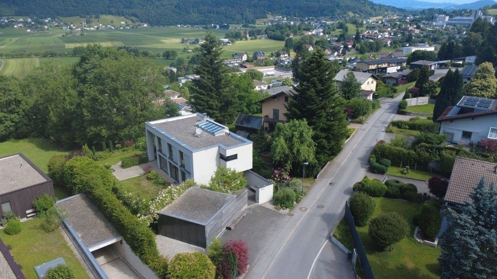 Panoramablick aus der Luft auf das moderne Haus, die Garage und die grüne Umgebung.