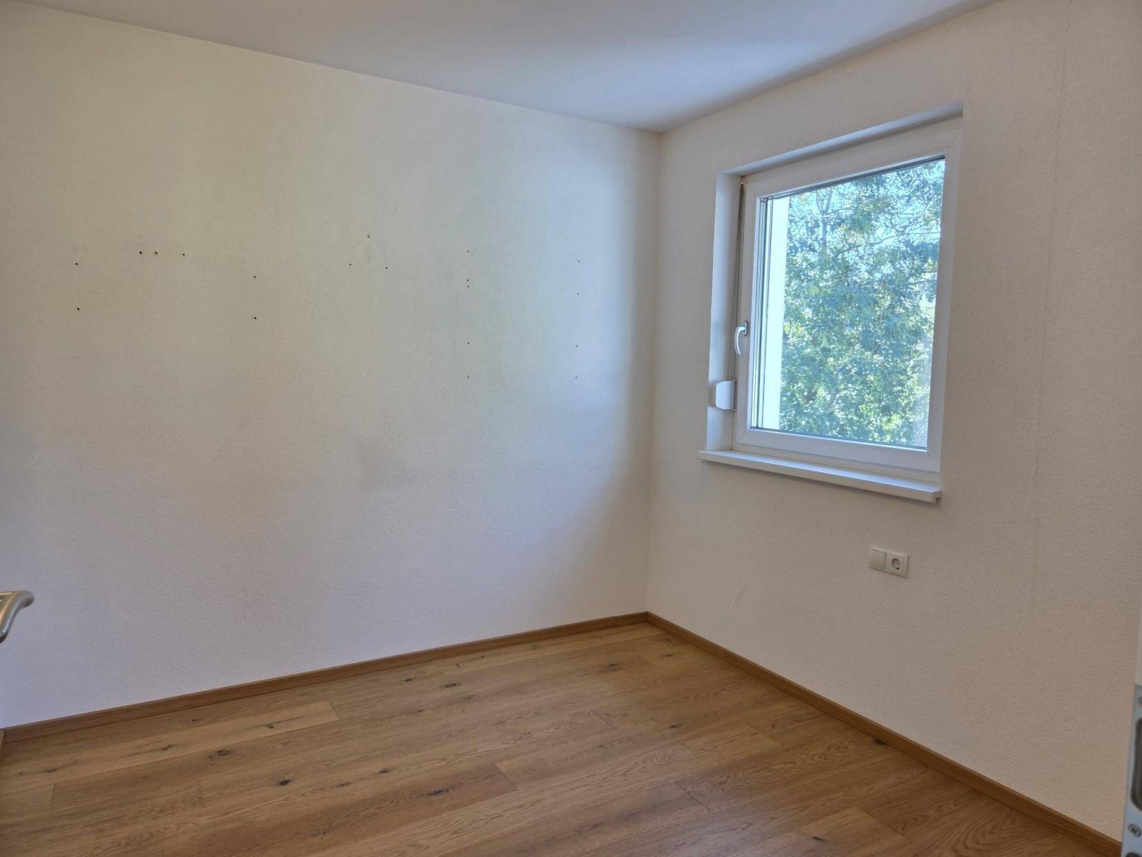 Helles Zimmer mit Eichenparkett und Fenster, ideal als Schlafzimmer oder Büro nutzbar.