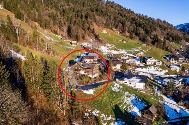 Weitläufige Ansicht des Bergdorfes mit dem markierten Grundstück und umliegender Natur.