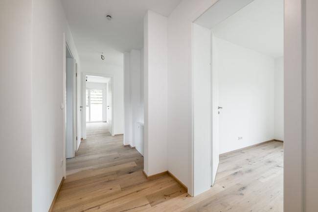 Heller Flur mit Holzboden und mehreren Türen, der zu den verschiedenen Räumen führt.