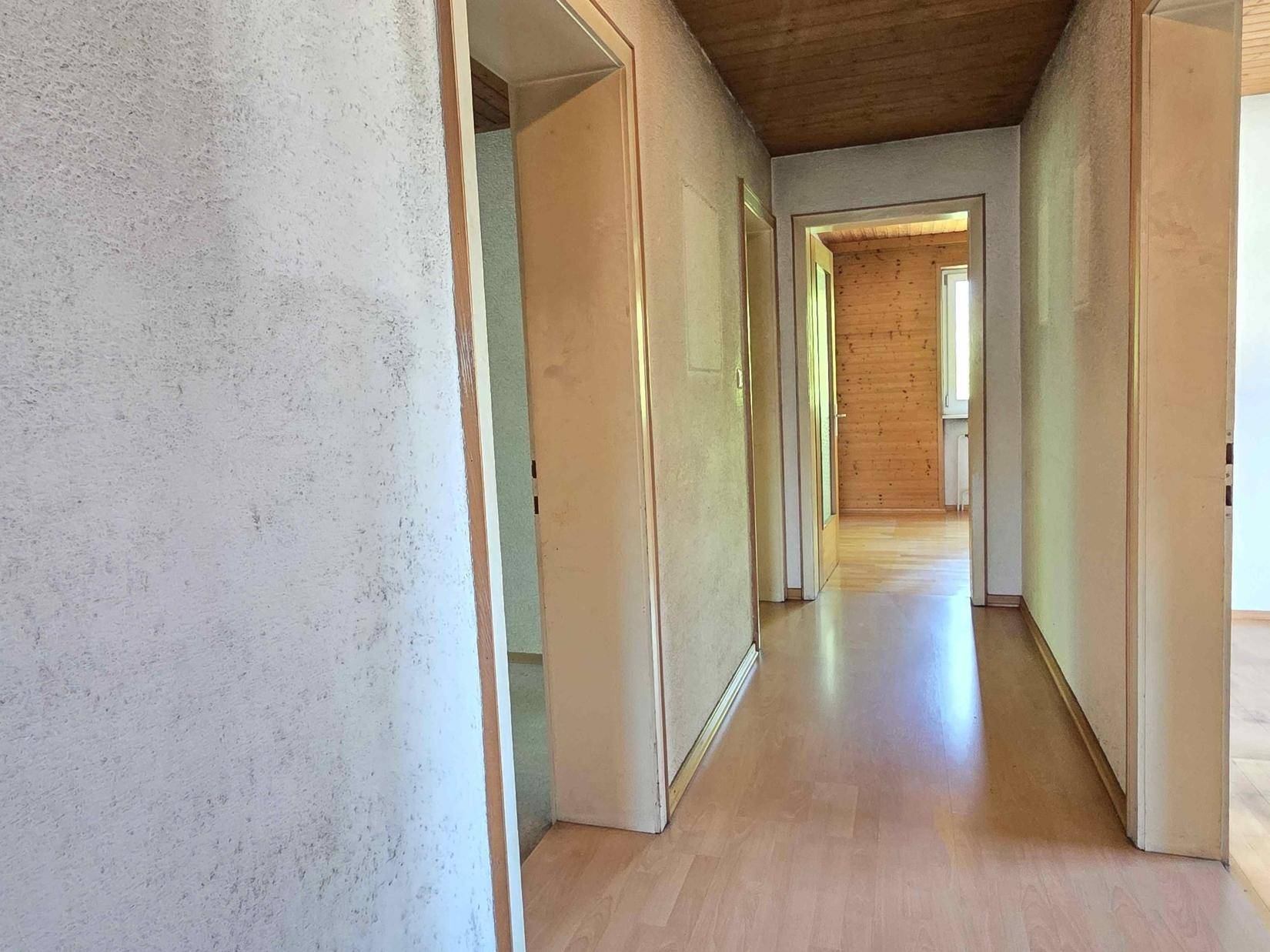 Langer Flur mit Laminatboden und mehreren Türen, der verschiedene Räume verbindet.