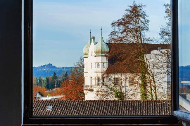 Malerischer Ausblick aus dem Fenster auf ein historisches Gebäude und die grüne Umgebung.