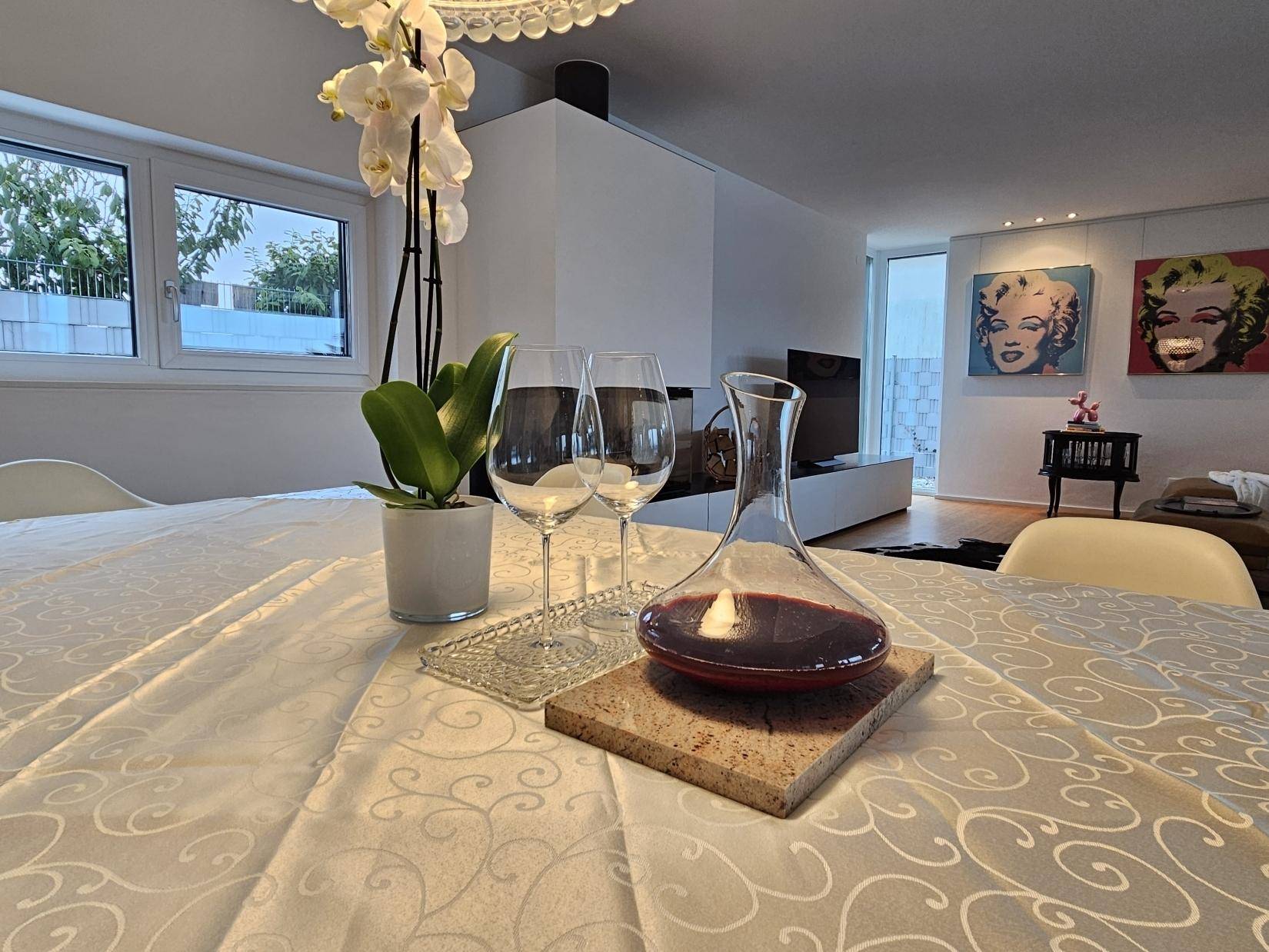 Detailaufnahme des Esstisches mit Weindekanter und Orchideendekoration.