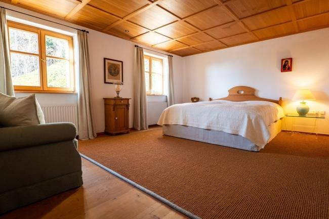 Geräumiges Schlafzimmer mit Holzkassettendecke, Doppelbett und einem Sofa, das zum Entspannen einlädt.