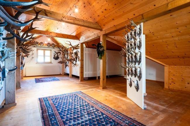 Großzügiger Dachboden mit Holzbalken und zahlreichen Hirschgeweihen als Dekoration, der einen rustikalen Charme versprüht.