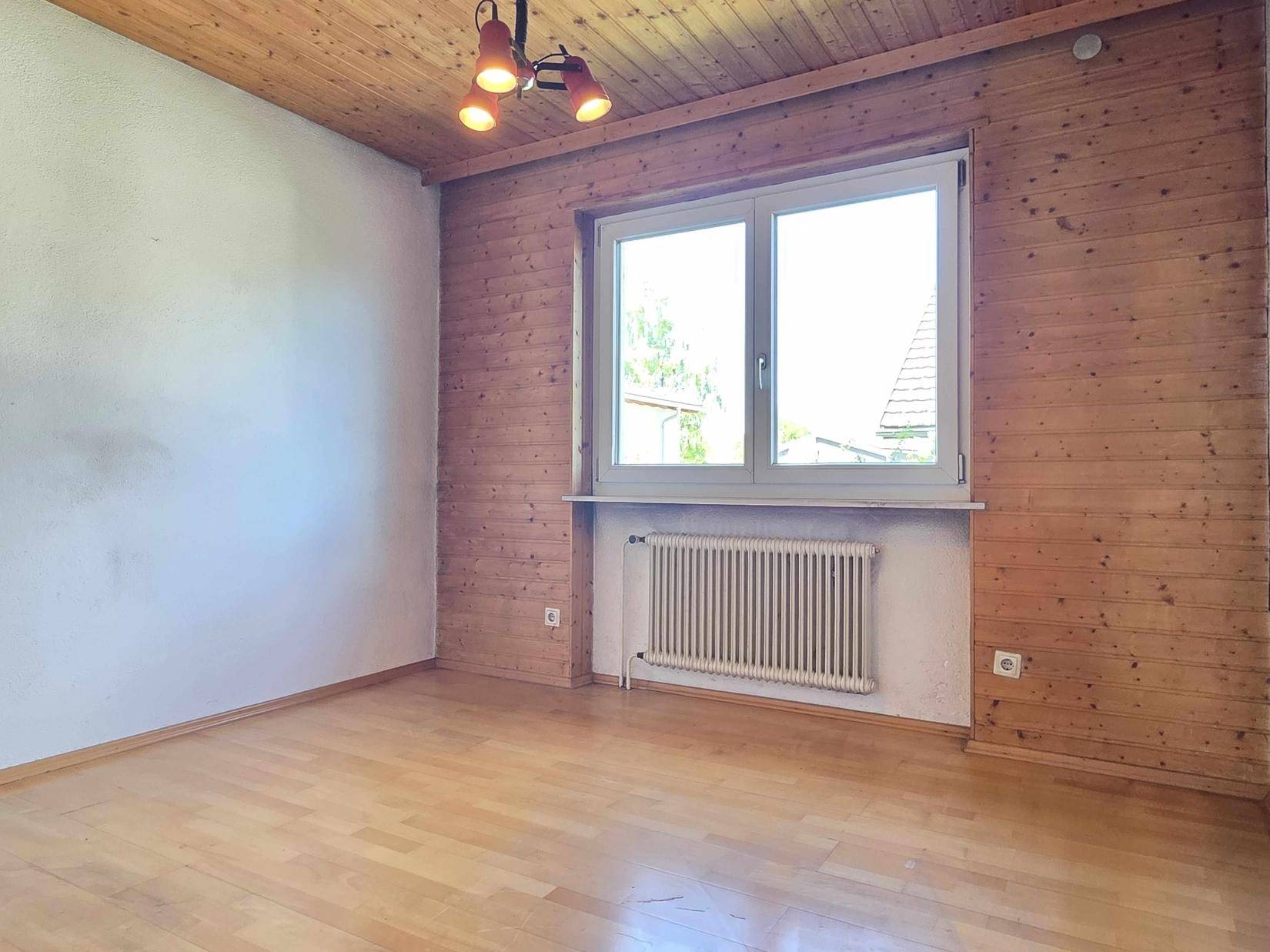 Schlafzimmer mit Holzwandvertäfelung, Holzdecke und hellem Laminatboden.