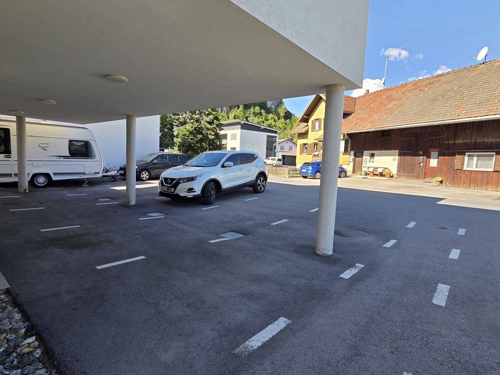 Überdachter Parkplatz unter dem Gebäude mit markierten Stellflächen für Fahrzeuge.