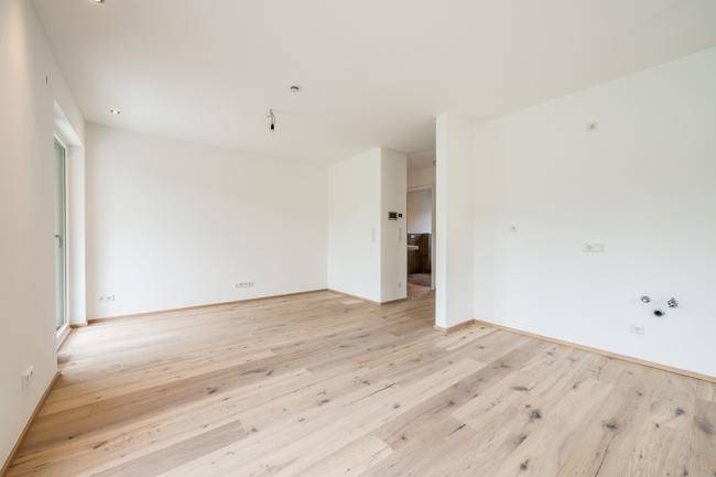 Offener Wohnbereich mit Parkettboden und Blick in den angrenzenden Flur.