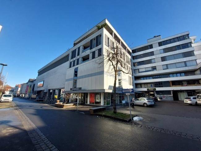 Weitläufige Ansicht des modernen Geschäftsgebäudes mit umliegender Straße und Parkplätzen unter blauem Himmel.