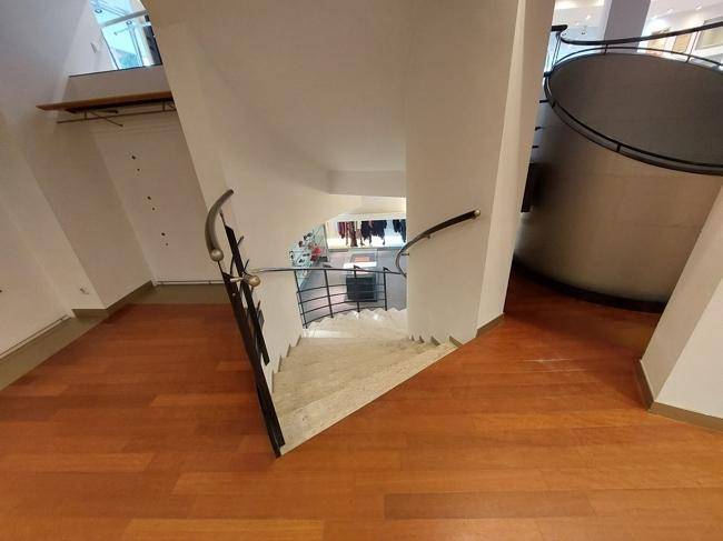 Elegante Treppe mit Holzstufen und Metallgeländer, die verschiedene Ebenen des Geschäfts verbindet.