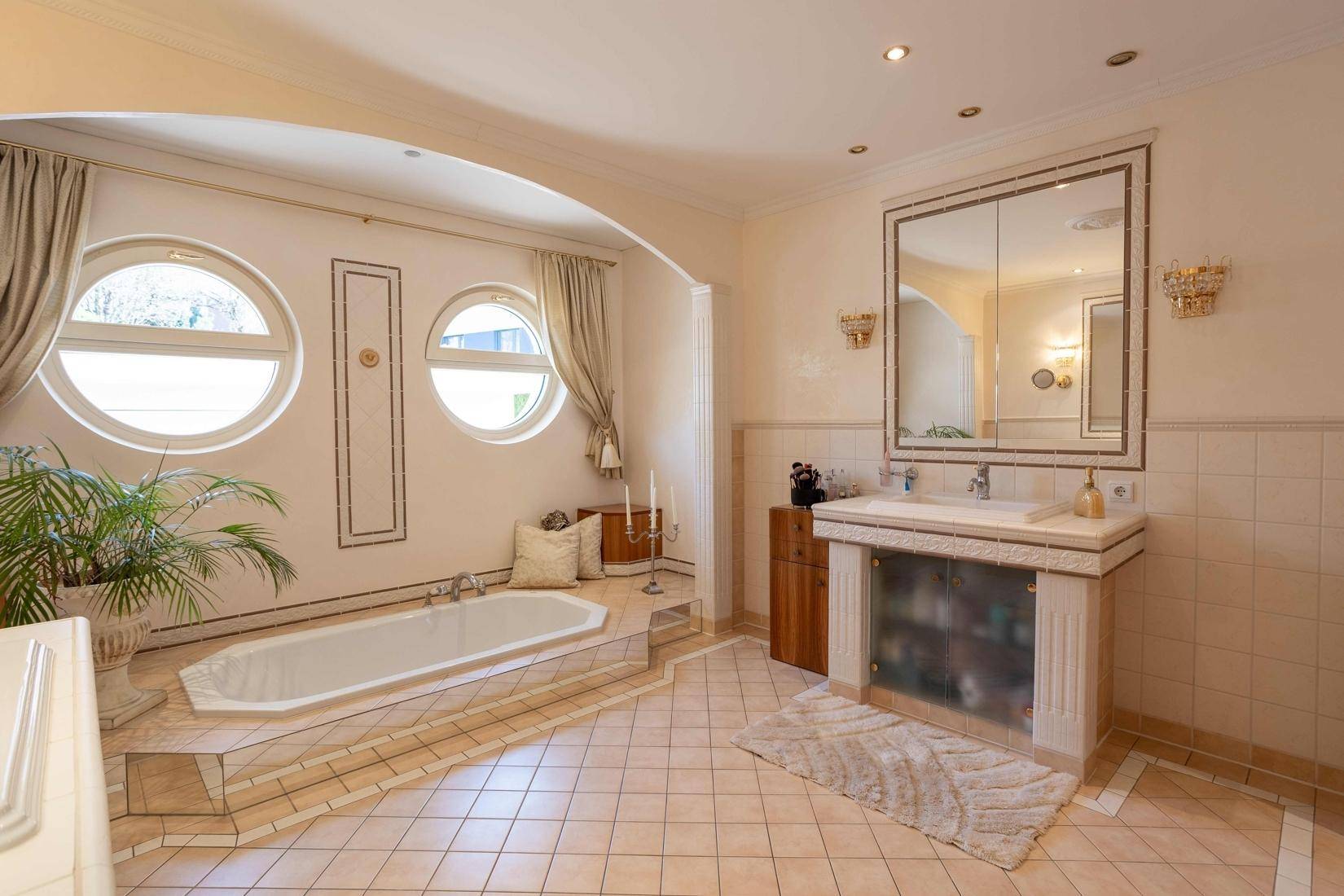 Großes Badezimmer mit Badewanne, Doppelwaschbecken und runden Fenstern.
