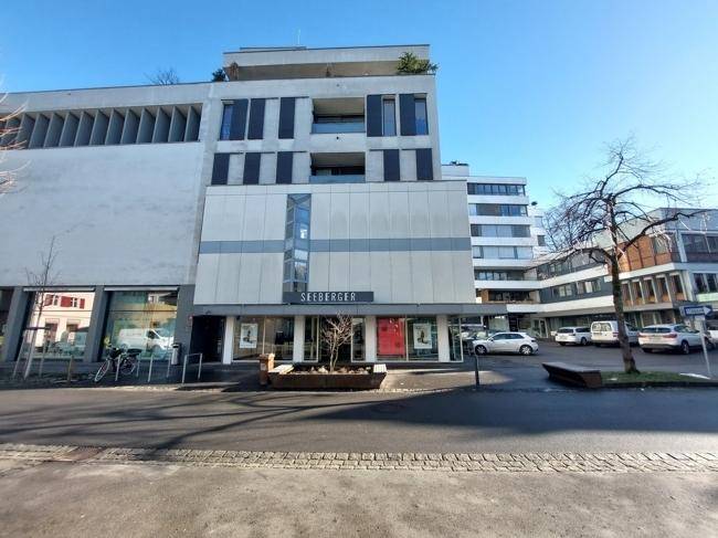 Weitläufige Ansicht des modernen Geschäftsgebäudes mit umliegender Straße und Parkplätzen unter blauem Himmel.