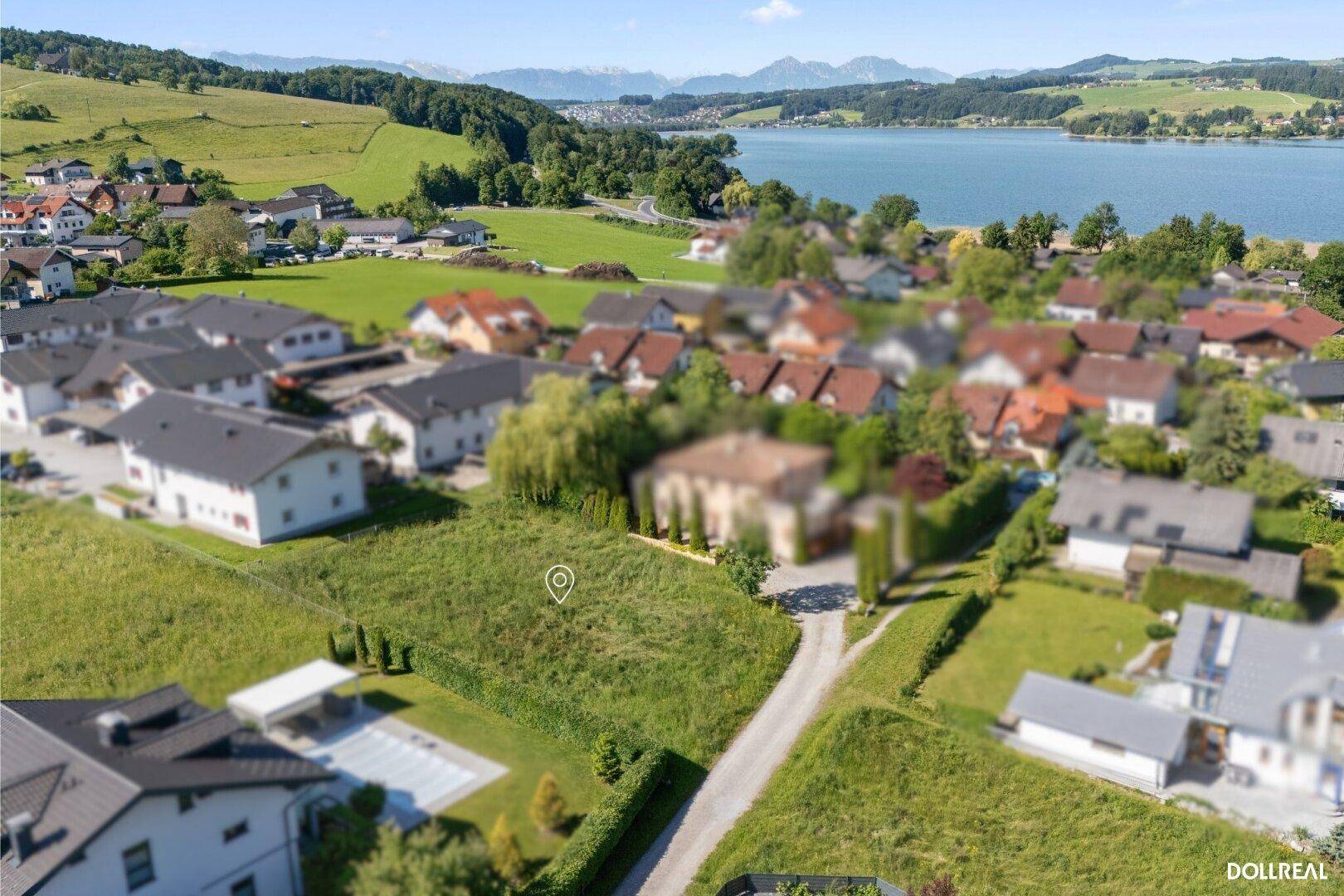 Übersicht des Baugrundstücks mit See- und Bergblick, umgeben von einer Wohnsiedlung.